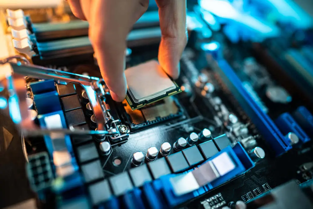 Mão instalando processador no soquete de uma placa-mãe de computador.