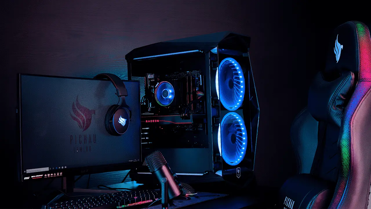 Setup gamer com PC RGB, monitor, headset, microfone e cadeira gamer iluminada.