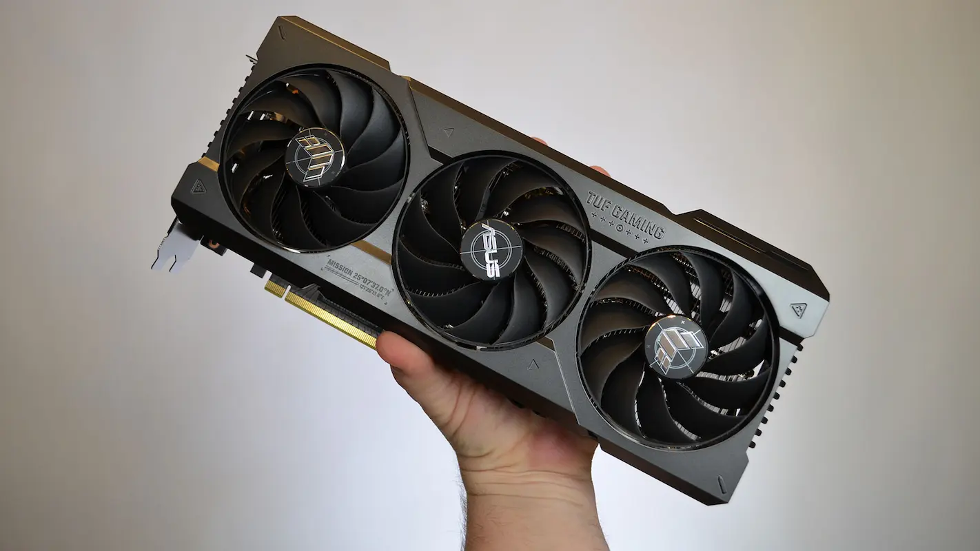 Placa de vídeo sendo segurada por uma mão em fundo cinza.