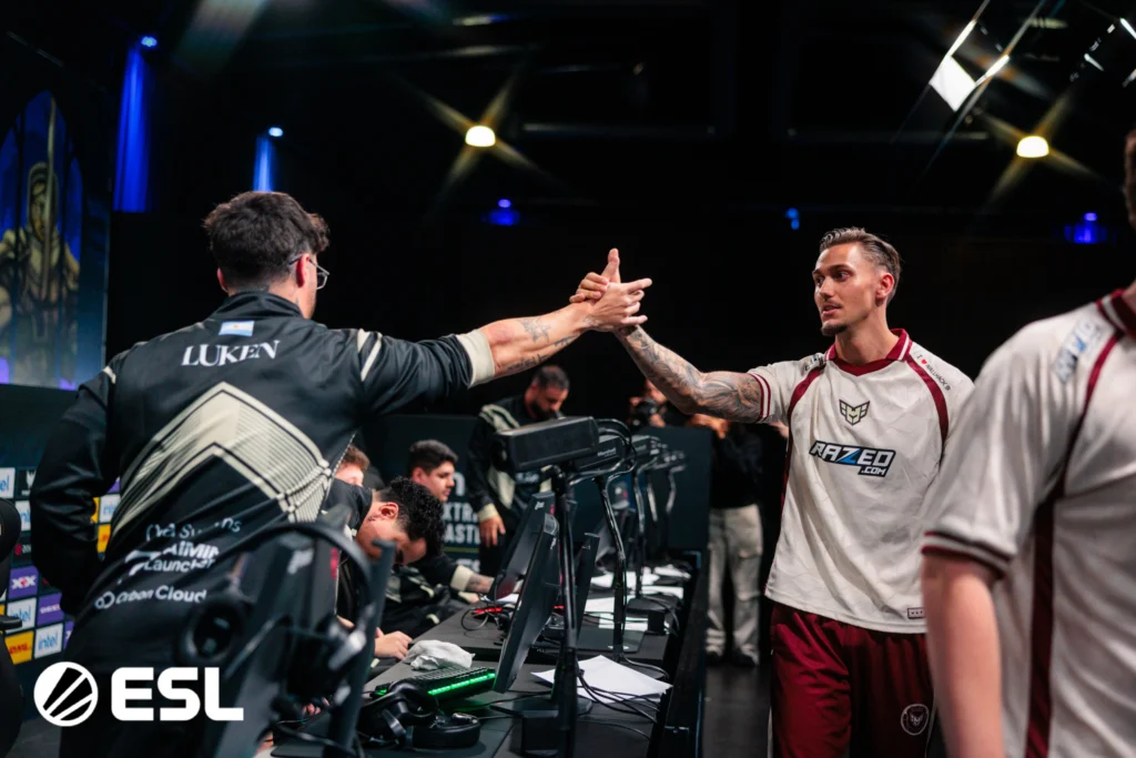 CS2: Segundo dia de Major termina com duas equipes eliminadas 3 Jogadores de Counter-Strike 2 (CS2) da Gaimin Gladiators e HEROIC se cumprimentando no IEM Cologne Major 2026.