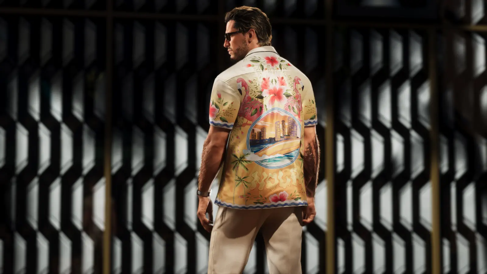Personagem masculino de GTA 6 visto de costas, usando camisa florida em ambiente sombreado.